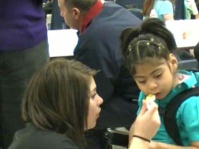 teacher feeding child in wheelchair